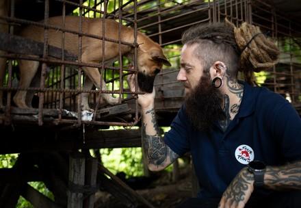 Un employé de QUATRE PATTES avec un chien dans une cage