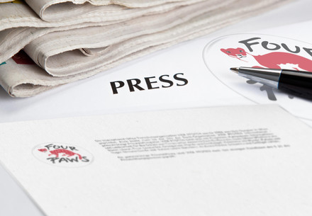 The text PRESS surrounded by newspapers and paper with the FOUR PAWS logo on it