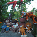 Many colourful crochet animals are draped on stone and in bushes.
